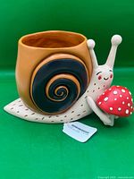 Front view of ceramic snail planter showing mushroom detail and planter opening