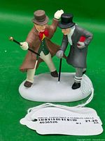 Full view of figurine on green background with tag visible