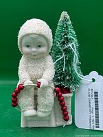 Front view of Snowbabies Cranberry Trimmings figurine with tag visible