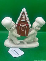 Front view showing two Snowbabies figures carrying gingerbread house, tag visible