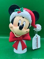Front view of Mickey Mouse resin tree topper with Santa hat and red bow