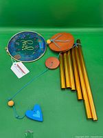 Overall components laid out: floral top disk, wooden disks, gold tubes, blue heart sail