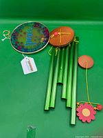 Entire wind chime unassembled showing glass panel, tubes, wood pieces, flower pendulum