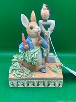 Front view showing Peter Rabbit with carrots and bird on spade