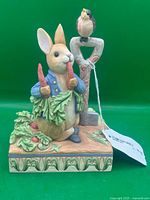 Front view of Peter Rabbit figurine holding carrots, bird on shovel