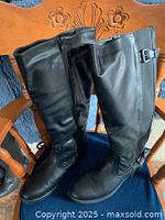 Front view of both black knee-high boots showing toe, shaft and buckles