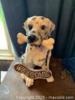 Front view of plaster dog statue with welcome sign