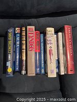 Spine view of ten hardcover books lined on dark surface