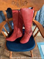 Pair of red knee-high boots on chair showing both boots