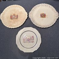 Front of three plates showing royal crest designs and rim styles