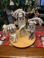 Three handmade wooden snowmen on round board
