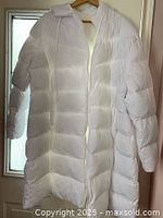 Front view of white puffer jacket hanging, showing length and quilting