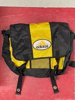 Front view showing yellow and black flap, Adidas logo, buckle straps