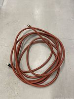 Coiled red rubber hose showing overall length and end fittings