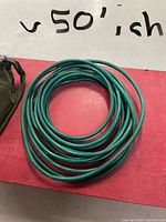 Coiled green garden hose on red surface