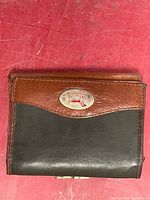 Front view of wallet showing two-tone leather and metal logo plaque