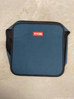 Front view of teal Ryobi square soft case showing logo and zipper edges