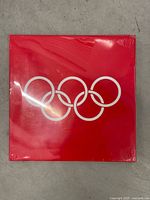 Front of sealed red hardcover with Olympic rings