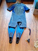 Full wetsuit laid flat with fins on legs and snorkel beside
