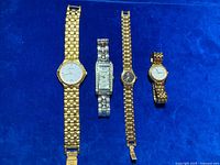 All four wristwatches laid out on blue background