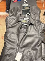 Two black leather jackets on hangers: Stormtech front visible, Scully behind