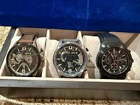 Three wristwatches in display case