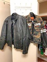 Both jackets hanging: black leather and camo Icon