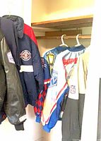 All four jackets hanging in closet showing fronts and patches