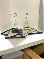 overview of two hummingbird feeders, three plant hanger brackets, one extension hook on table