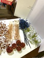 Assorted decorative sprays, garlands and pinecone ball ornaments laid out on table