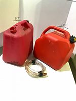 overview of two red fuel cans and clear hose