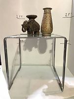 Front view of glass table with vase and elephant candle holder on top