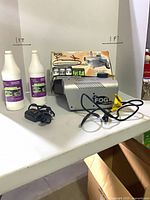 Fog machine, remote, two bottles of fog fluid on table
