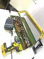 Lot overview showing DeWalt drill, socket tray, hacksaw, rotisserie spit