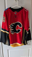 Full front view of Adidas Calgary Flames #79 Ferland jersey on hanger