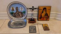 Group shot of all items: plate, tray, crucifix, two wood icons, metal plaque, ribbon