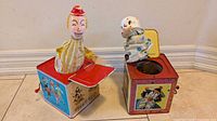 Both jack-in-the-box toys side by side, lids open, clowns visible