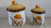 Two Merry Mushroom canisters side by side front view