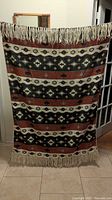 Full view of woven blanket hanging to show pattern and fringe