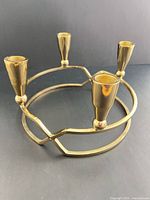 Angled view of brass-toned circular candle holder showing four cups and ring base