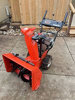 Front left view of Ariens Compact 24 snow blower with chute, auger, tire chains visible