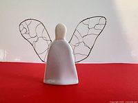 Front view of ceramic angel figurine showing body, head, and wire wings