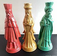 Front view of three glazed ceramic wise men candle holders in red, gold and green