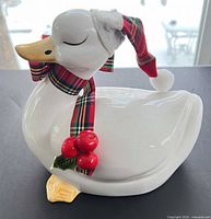 Front left view of ceramic duck figurine showing scarf, hat, holly berries