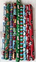 Nine partial rolls of gift wrap standing upright