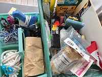 Overall view of two teal totes with glue guns, yarn, Crayola packs and other supplies