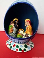 Front view of hollow painted eggshell showing interior nativity figures on pedestal base