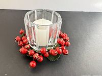 Front view of glass holder with candle and berry wreath