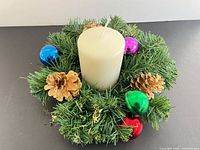 Wreath with candle, ornaments and pinecones top view