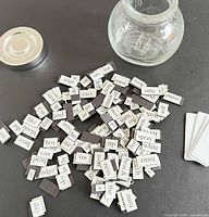 pile of magnetic word tiles spread on surface next to glass jar